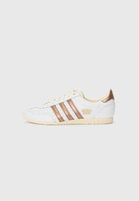 Adidas sportiv alb cu trei dungi metalice de culoare roz auriu, detalii perforate, talpă de culoare crem și logo-ul "adidas JAPAN" în auriu pe lateral.