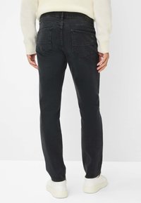 Jeans in denim nero a gamba dritta, con due tasche posteriori e una consistenza sottile. Indossati con sneakers bianche e un maglione chiaro.