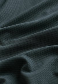 Tumehall kangas peene diagonaalse ruudustiku mustriga, esitatud pehmetes voltides ja kergete tekstuurivariatsioonidega.