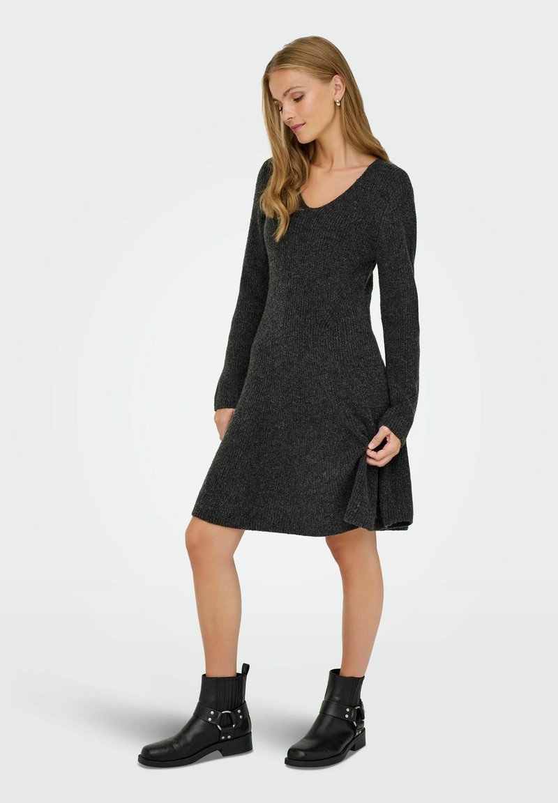 Robe gris charbon à manches longues, corsage ajusté et jupe évasée. Texture côtelée et décolleté en V, associée à des bottines noires.