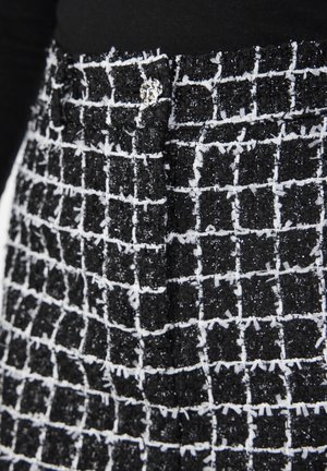 Fekete-fehér mintázatú anyag, textúrált felülettel, rácsos mintázattal és fényes ezüst díszítéssel a derékrészen.