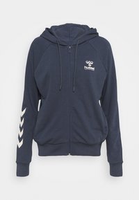 Felpa con zip color blu navy, dotata di tasca a marsupio, cappuccio con cordino e logo bianco; presenta un motivo a chevron bianco su manica sinistra.