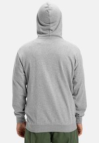 Sivá mikina s jemnou textúrou, s kapucňou na stiahnutie, dlhými rukávmi a elastickými manžetami a spodným lemom. Žiadne grafické alebo dizajnové detaily nie sú viditeľné.