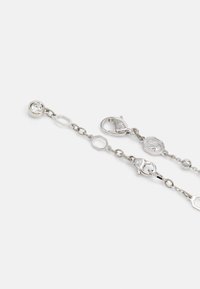 Pulseira de corrente prateada com elos hexagonais, pendente redondo com gema transparente e fecho tipo lagosta. Textura metálica suave.