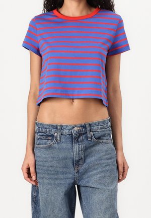 Lyhyt t-paita, jossa on sinisiä ja punaisia vaakaraitoja, lyhyet hihat ja pyöreä kaula-aukko, yhdistettynä korkeavyötäröisiin vaaleansinisiin farkkuihin.