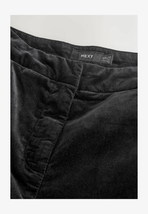 Black velvet skirt with a smooth texture, featuring a clean waistband and visible stitching details. Brand label "NEXT" is attached.