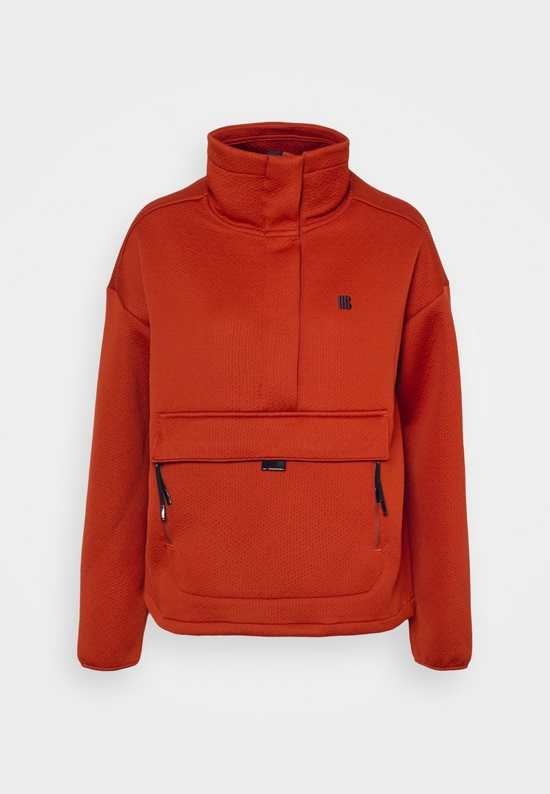 Orange pulloverjacka med hög krage, texturerad tyg, framficka med dragkedja och en liten logotyp på bröstet. Har långa ärmar.