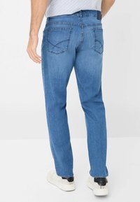 Jeans di denim azzurro chiaro con taglio dritto, tasche posteriori con cuciture intricate e vita a media altezza.
