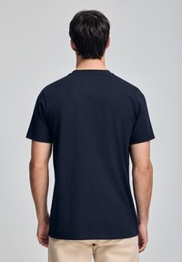 Marinblå t-shirt med rund halsringning, kort ärm, gjord av ett slätt material. Ren, minimal design, utan synliga logotyper eller mönster.