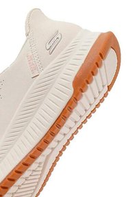 Jasno beżowe sneakersy z teksturowaną cholewką, gumową podeszwą z pomarańczowymi akcentami oraz widocznymi żłobionymi wzorami dla lepszej przyczepności.