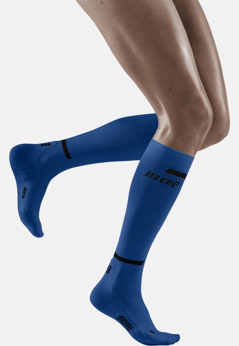 Blaue knielange Kompressionssocken mit einem strukturierten Muster, schwarzem Akzentband und Logodetail an der Wade und der Sohle.