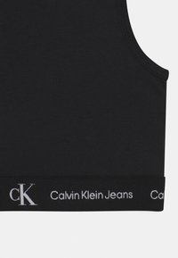 Czarny krótki top z elastycznego materiału z logo "Calvin Klein Jeans" w białym kolorze. Posiada dopasowany krój oraz klasyczny dekolt.