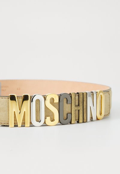 Ζώνη σε καφέ σουέτ με μεγάλα, έντονα γράμματα που γράφουν "MOSCHINO" σε χρυσό, ασημί, μαύρο και λευκό. Διαθέτει ομαλή υφή και κλασικό σχέδιο.