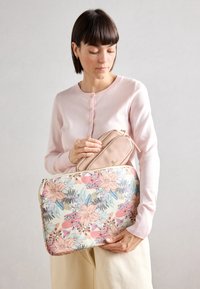 Sac à motif floral aux couleurs pastel ; présente une texture lisse et une fermeture éclair. Petite pochette beige clair placée à l'intérieur.