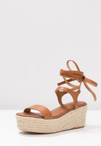 Brun läder kilklack sandal med ankelband, jute-inbäddad mittsula, slät textur, öppen tå och en mjuk fotbädd.