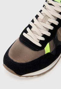 Čierne zamatové tenisky s hnedým syntetickým zvrškom, neonovo zelenými akcentmi, krémovými šnúrkami a textúrovanou gumenou podrážkou.