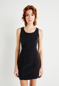 Μαύρη τζιν φόρεμα με εφαρμοστή γραμμή, φαρδιά μανίκια και τετράγωνη λαιμόκοψη. Διαθέτει ορατές ραφές και στρίφωμα που τελειώνει στο μέσο του μηρού.