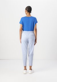 Blå kortermet topp, lyseblå smale bukser med elastisk midje, kombinert med hvite joggesko. Enkel, moderne design.