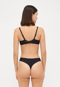 Zwart lingerieset met een eenvoudige bh met verstelbare bandjes en een haaksluiting, gecombineerd met een lage slip. Glad textuur, minimalistisch ontwerp.