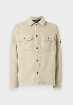 Fleece jas in licht beige, met een kraag, twee borstzakken met kleppen, zwarte knopen en een zachte, gestructureerde oppervlak.