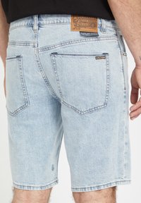 Lyseblå denimshorts med en afslappet pasform, med et lædermærke på bagsiden, fem lommer og diskrete syninger.