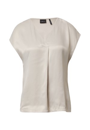 Blouse en satin beige avec un col en V, des manches dolman courtes et un pli central. Texture lisse ; design minimaliste sans motifs ni accents.