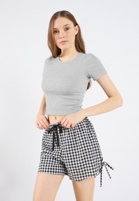 Gray ribbed crop top paired with black and white checkered shorts featuring a drawstring waist and side ties.