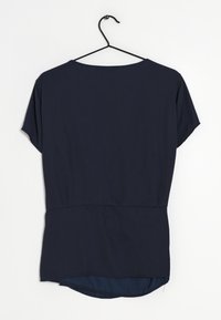 Top blu navy a maniche corte con una vestibilità ampia, caratterizzato da un collo rotondo e un orlo posteriore leggermente più lungo. Tessuto dalla texture liscia.