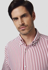 Biała koszula w pionowe czerwone paski, z kołnierzykiem zapinanym na guziki, wykonana z bawełny, z standardowym krojem i dwoma guzikami z przodu.