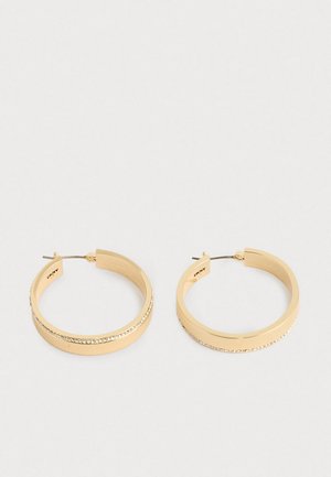 Une paire de boucles d'oreilles créoles en ton doré avec une rangée de petites cristaux le long du bord extérieur, présentées sur un fond clair et uni.