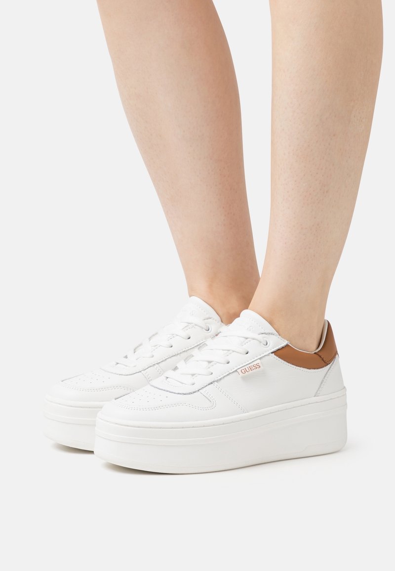Weiße Plattform-Sneaker mit braunen Lederakzenten, runder Zehenpartie, durchbrochener Struktur und Markendetail an der Seite. Schnürdesign.