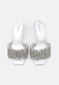 Sandales à talons block argentées avec une large bride ornée de rhinestones et une finition en satin lisse, présentant une ouverture au niveau des orteils et un design sans dos.