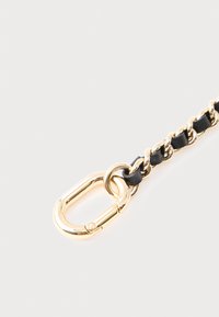 Μαύρο δερμάτινο λουράκι με αλυσίδα και μεταλλικές χρυσές λεπτομέρειες, με εμφανή οβάλ καραμπίνερ και σχεδιασμό με στριφτά συνδετήρια κρίκα.