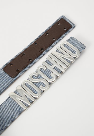 Džinsinio diržo su ruduo odiniu pamušalu ir didelėmis sidabrinėmis raidėmis, rašančiomis „MOSCHINO“, ant baltos fono.