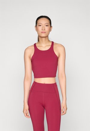Bordo sportski crop top s širokim naramenicama i prilagođenim dizajnom, uparen s odgovarajućim tajicama visokog struka koje imaju detalje šavova.