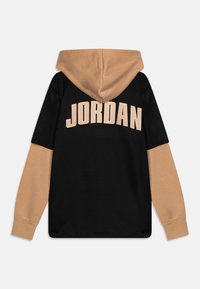 Sudadera con capucha que presenta un cuerpo negro y mangas beige, con "JORDAN" en grandes letras color crema en la parte posterior.