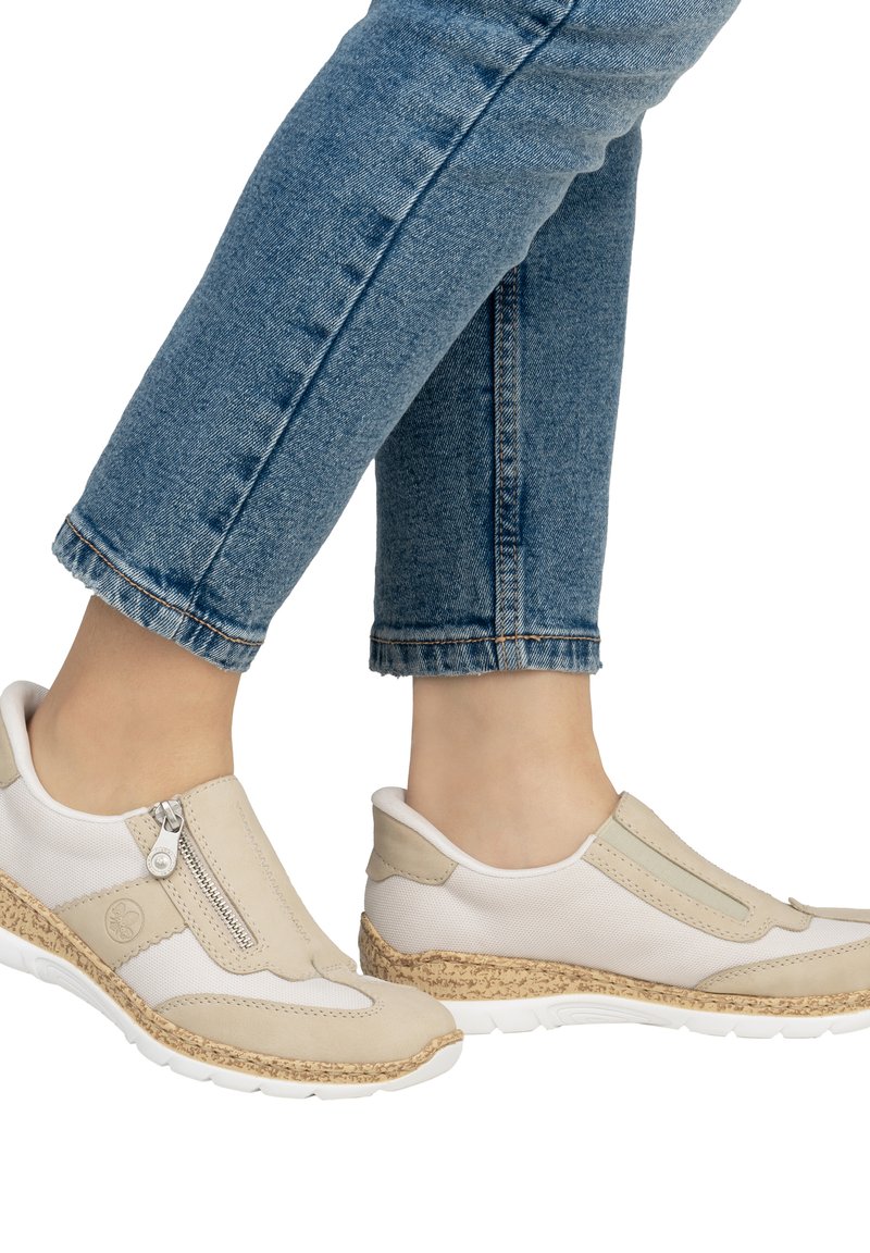 Bottines beiges sans lacets avec un détail zip, matériaux combinés comprenant un maillage doux et du cuir lisse, et une semelle texturée ressemblant à du liège.