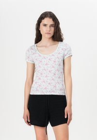 Top azzurro chiaro a maniche corte con un motivo floreale, texture a costine e scollatura a girocollo, abbinato a pantaloni corti all'uncinetto neri.