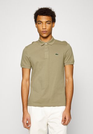 Oliven grøn polo skjorte lavet af bomuld, med klassisk krave, tre-knaps placket og broderet logo på brystet. Korte ærmer.