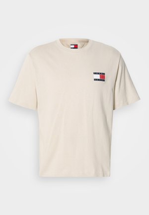 T-shirt di cotone color crema con maniche corte, caratterizzata da una piccola toppa con il logo a strisce rosse, bianche e blu scuro sul petto sinistro.