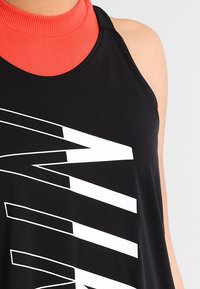 Schwarzes ärmelloses Oberteil mit hohem roten Kragen, das mit einem auffälligen weißen Grafiktext-Design versehen ist. Glatte Textur mit sportlichem Stil.