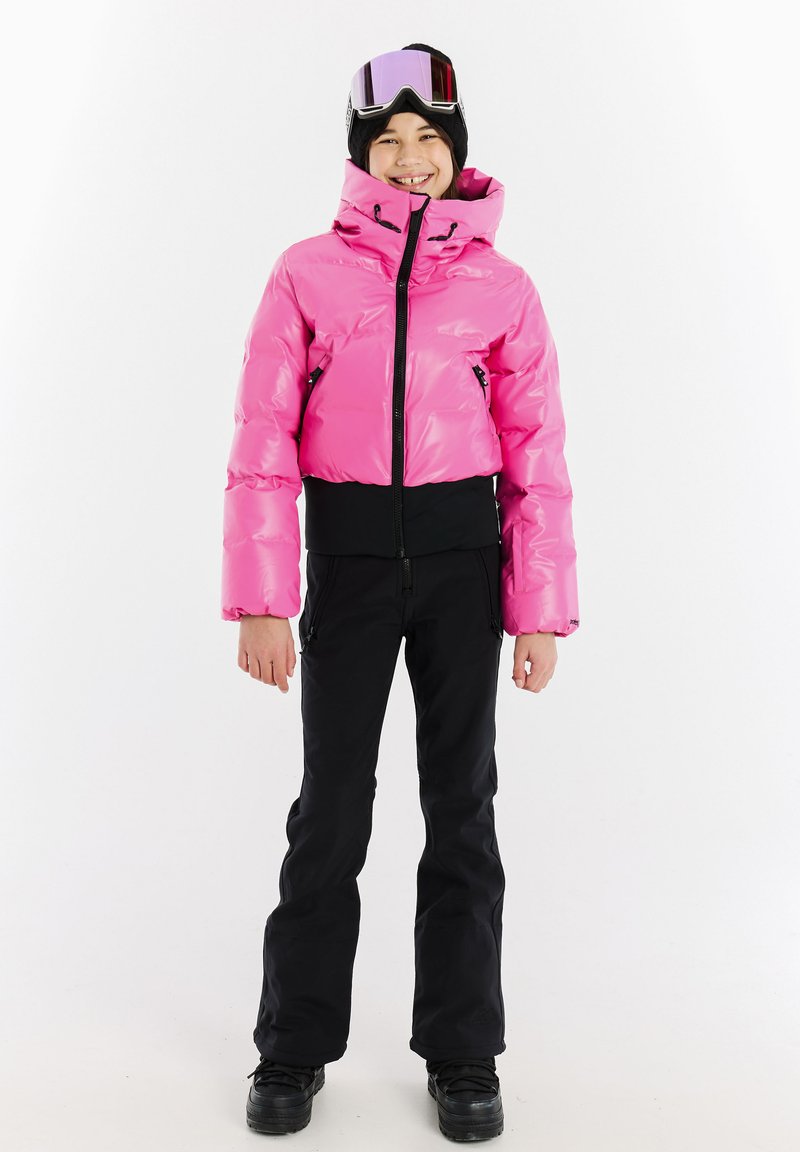 Rosa Pufferjacke mit tailliertem Design, hohem Kragen und schwarzen Akzenten, kombiniert mit schwarzen Skihosen und schwarzen Stiefeln. Schneebrille auf dem Kopf.