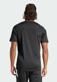 Camiseta deportiva negra hecha de tela ligera, con mangas cortas y cuello redondo; textura lisa sin patrones ni detalles visibles.