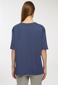 T-shirt in cotone blu navy con maniche corte, vestibilità corta, scollatura rotonda e una consistenza liscia. La vista di retro mostra un colore uniforme senza motivi.