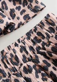Látka s leopardím vzorem v odstínech růžové, černé a béžové, se sbíranou texturou a naříznutými okraji. Měkký a lehký materiál.