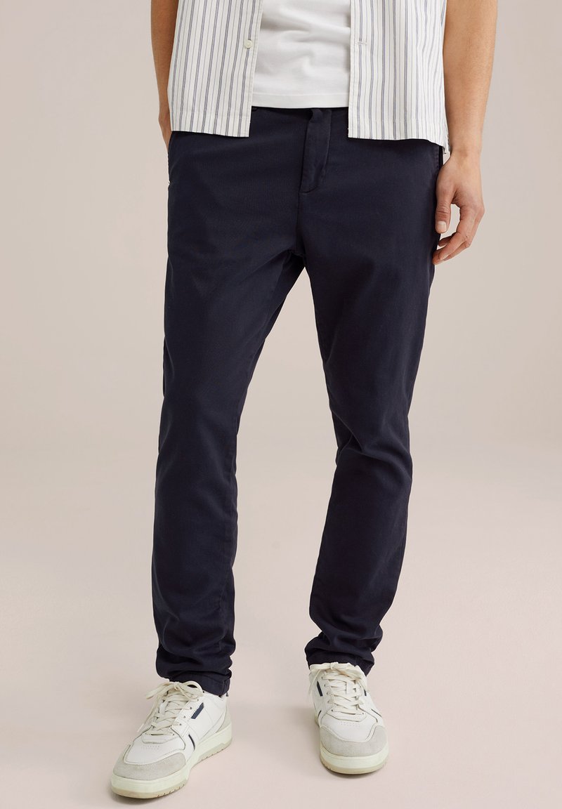 Pantaloni navy din bumbac ușor, cu un design drept, buzunare frontale și o textură subtilă, asortați cu adidași albi.