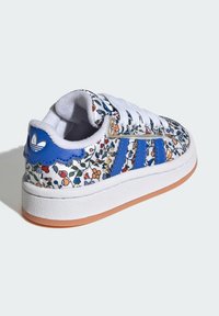 White sneakers with blue stripes and floral pattern. Features a textured white midsole and gum outsole. Blue heel tab with logo.