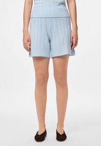 Gaiši zili adīti šorti ar rakstu un taisnu griezumu, ar viegli izteiktu ribotu jostasvietu un sānu kabatām.