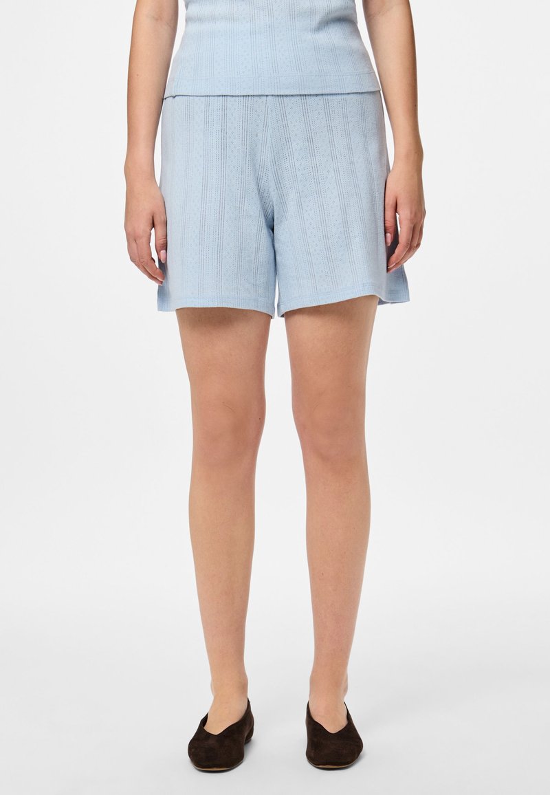 Gaiši zili adīti šorti ar rakstu un taisnu griezumu, ar viegli izteiktu ribotu jostasvietu un sānu kabatām.