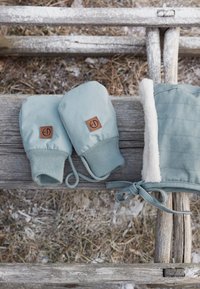 Ljusblå vantar med elastiska manschetter och en tanfärgad logopatch, tillsammans med en matchande blå hatt med vit fleecefoder och en knytning.